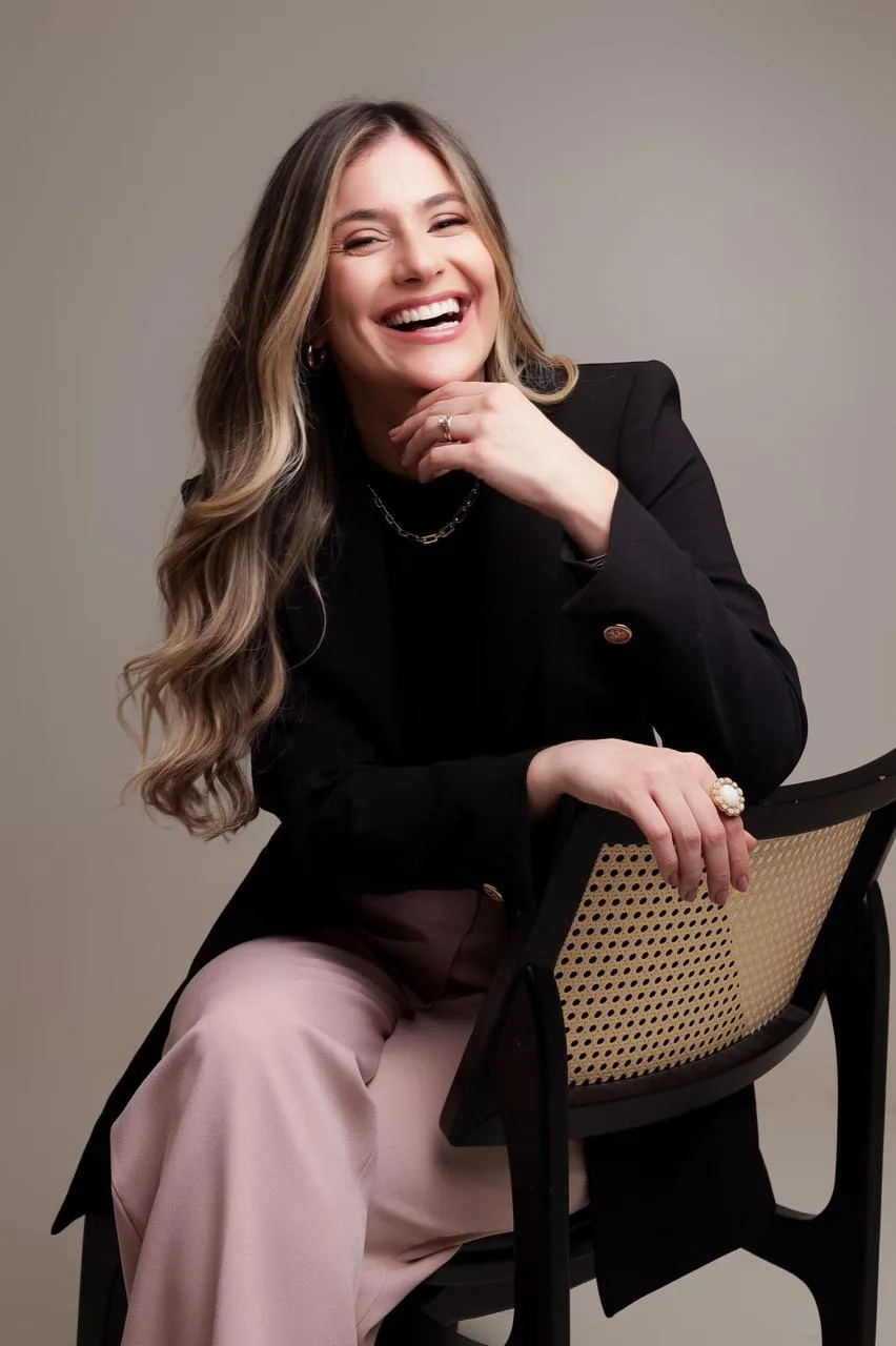 Dra. Melina de Paula Ribeiro sorrindo, sentada